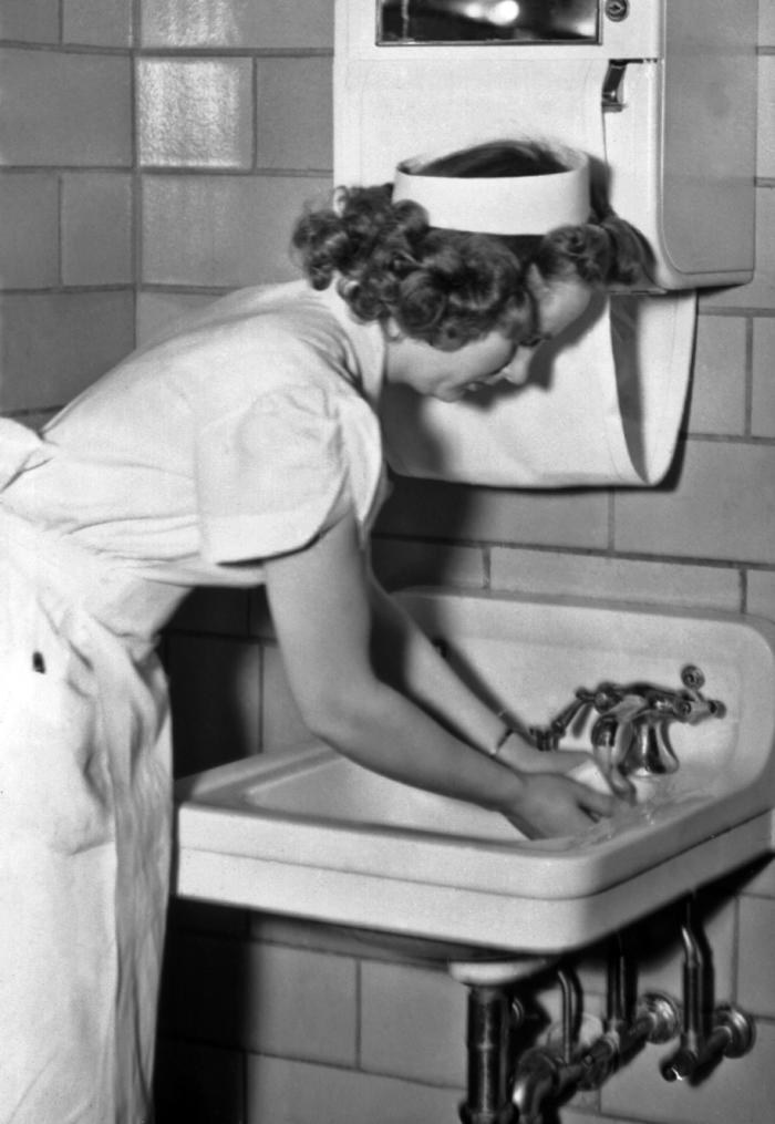 Historic 1930s photograph of a nurse washing her hands (public‑health hand hygiene illustration)